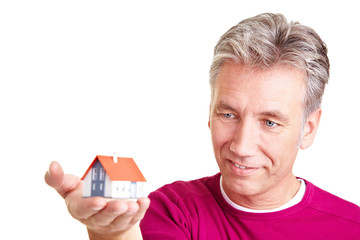 Mann schaut Miniaturhaus an