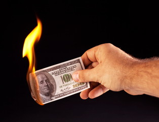 burning dollar in hand isolated on a black
