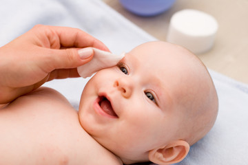 cleaning baby 's eye with cotton pad - obrazy, fototapety, plakaty