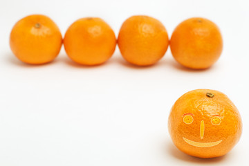 Tangerine with funny face blurred row of mandarins in back