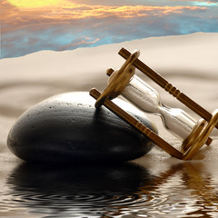 Sanduhr im Sand mit Himmel und Wasser