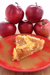 Apple Pie-slice on a plate with cinnamon and some red apples