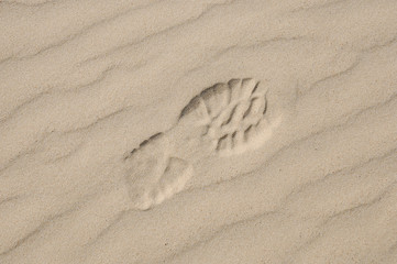 Footprint on light sand with diagonal pattern