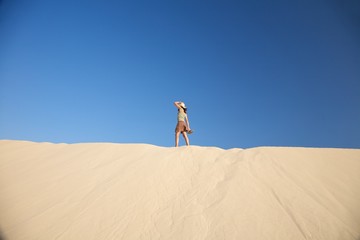 woman with hat on dune