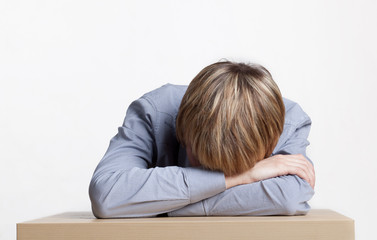 young boy asleep at a table with his head in his hands