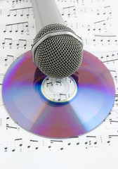 Silver microphone and cd on sheet of notes
