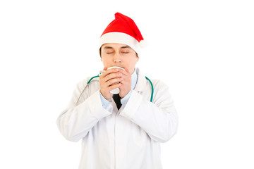 Medical doctor in Santa hat enjoying cup of hot coffee