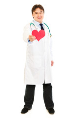 Smiling medical doctor holding paper heart in hand