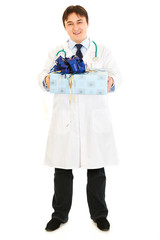 Smiling medical doctor holding present in hands