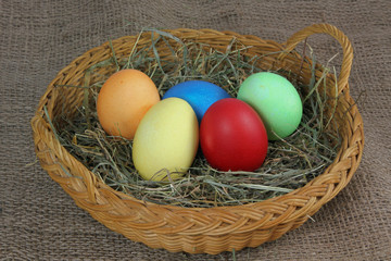 bunte Ostereier in einem Korb mit Heu