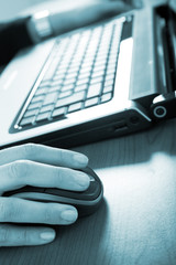 Blue toned image of a man typing on the laptop