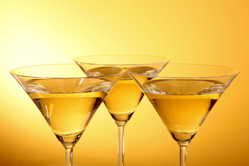 Three glasses of martini on a yellow background