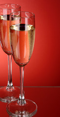 Two glasses of champagne on a red background