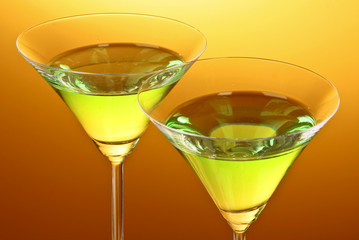 glass with a green alcoholic beverage to a yellow-brown backgrou