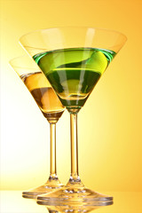 glass with a green alcoholic beverage to a yellow-brown backgrou