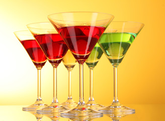 a few glasses of alcoholic drinks in a yellow-brown background