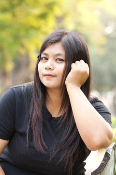 Woman sitting in a public park is roll her hair..