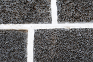 Fototapeta premium Dark volcanic bricks with white cement joints, pattern