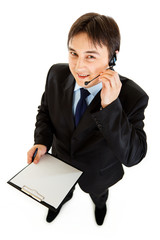 Smiling businessman with headset holding blank clipboard