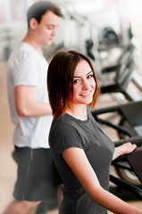 Beautiful girl running on a treadmill in sport club