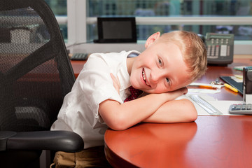 Cute young boy in a business office with funny expression