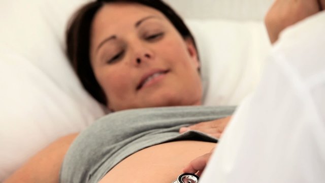 Nurse listening to the belly of her pregnant patient
