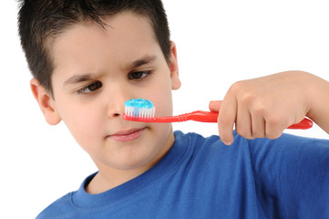Cross eyed boy brushing teeth isolated on white background.