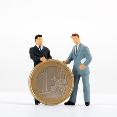 Figurines of businessmen with one euro coin