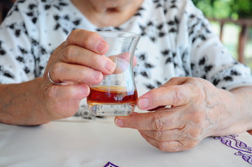 a wrinkled hand holds a glass of tea