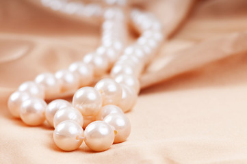Pearl necklace on the bright satin background