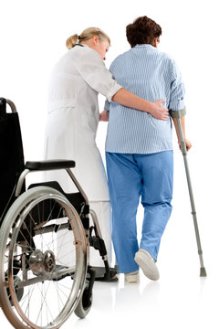nurse helps a senior woman on crutches in hospital