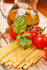 pasta, olive oil and tomatoes on the wood background
