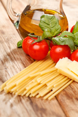 pasta, olive oil and tomatoes on the wood background