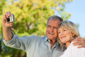 Fototapeta premium Smiling couple taking a photo of themselves in the park