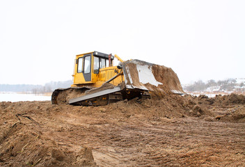 A yellow bulldozer working in the winter