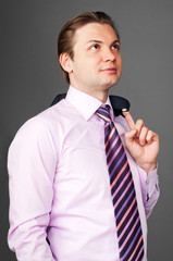 Young handsome serious businessman on the gray background