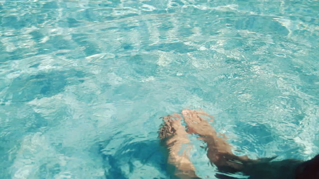 Man's feet splashing water in swimming pool