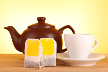 Close-up of tea bag and teapot on yellow background