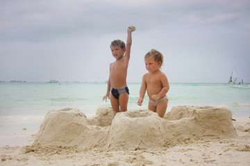two children building sand castle on beach