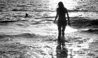 Young woman silhouetted and reflected in the sea