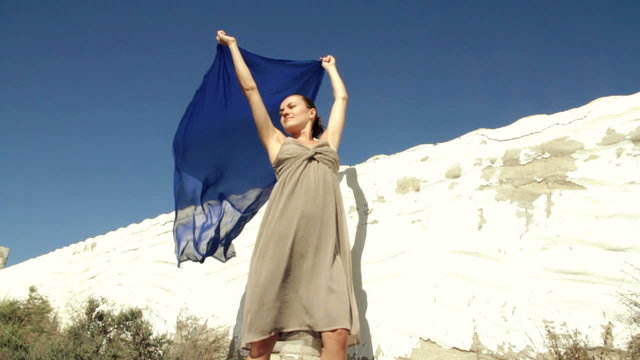 Woman with waving sarong against the blue sky, slow motion
