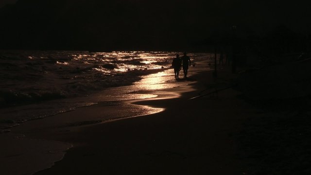 People walk on the beach at sunset