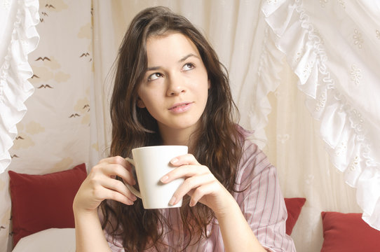Mädchen mit Kaffeebecher im Bett