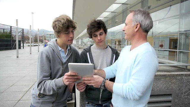 Teenagers and teacher using electronic tablet