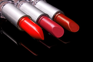 three bright lipsticks on a black background