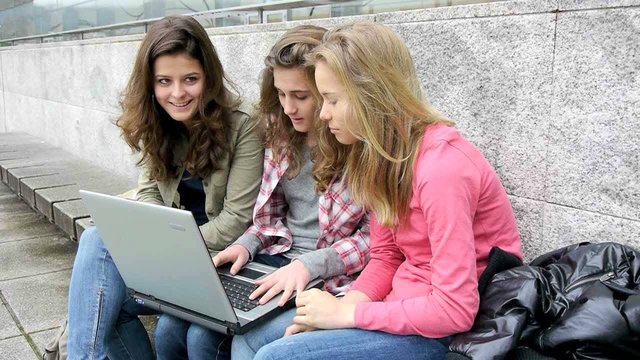 Teenage girls with laptop computer in school yard