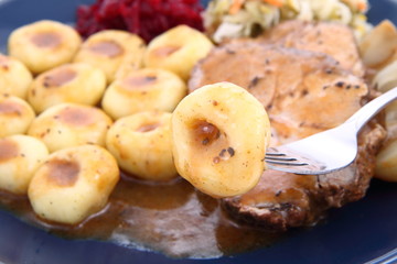 Pork steak and dumplings being eaten with a fork