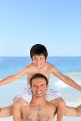 Fototapeta na wymiar Father having son a piggyback on the beach