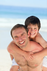 Fototapeta premium Father having son a piggyback on the beach