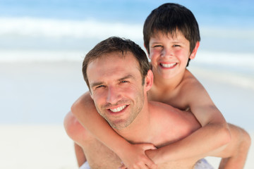 Father having son a piggyback on the beach